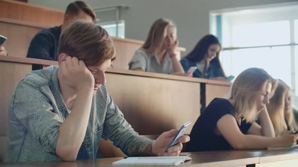 A Boring Lecture at the University Students Look at the Screens of Smartphones