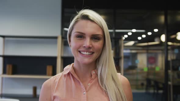 Caucasian businesswoman walking looking at camera and smiling in modern office