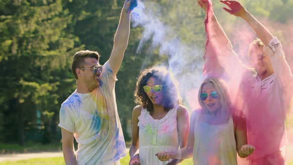 Couple of Guys Spraying Colorful Powder in the Air and at Their Girlfriends