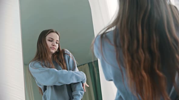 A Young Woman in Blue Sweater Dances in Front of a Mirror