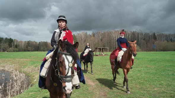 Females in a Bright Medieval Costumes Rides a Horses Through a Field Reconstruction Medieval Women