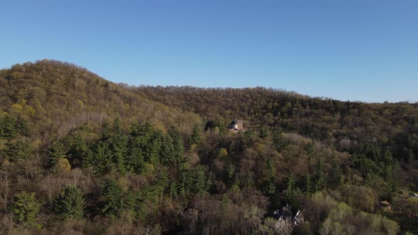 Overview of catholic shrine built into the side of a mountain with forest all around with a blue sky alt