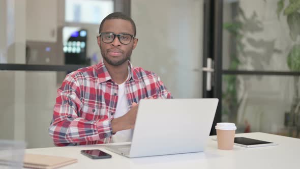 African Man Looking at Camera While Using Laptop