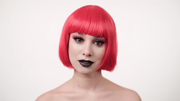 Woman in a pink bright wig at a party. She is smyling and having fun. Close-up of the face