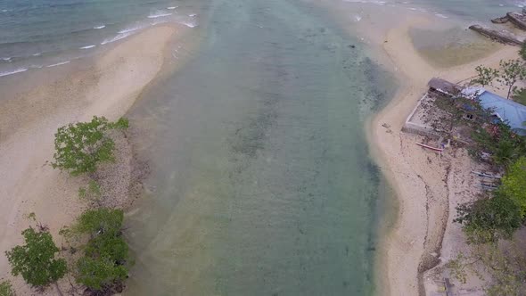 Beautiful aerial shot descending over a small canal along the coast of Cebu and tilting up to reveal