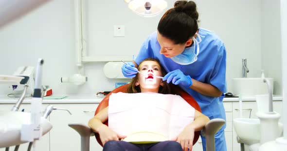 Dentist examining a young patient with tools