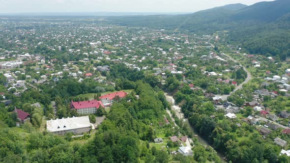 Aerial Drone Footage of a City Surrounded By Green Mountains