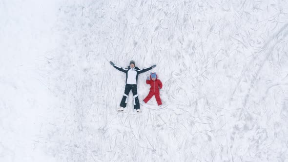 Woman and Kid Lying on Ice in Rink