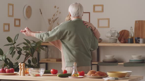 Cheerful Senior Couple Cooking and Dancing in Kitchen