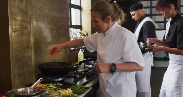 Caucasian female chef teaching diverse group preparing dishes and smiling