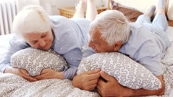 Senior couple interacting while relaxing on bed