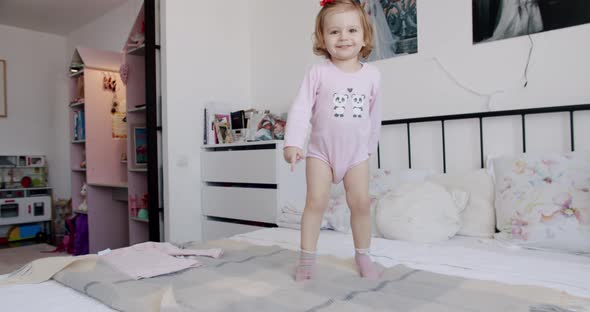 The 1Yearold Girl Plays at Home Jumps for Joy and Smiles Beautifully