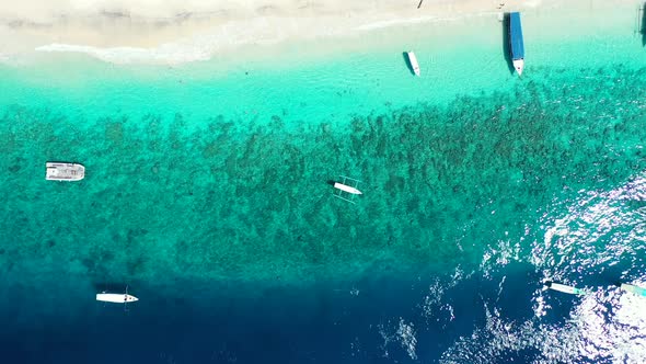 Wide overhead island view of a white sandy paradise beach and aqua blue water background in high res