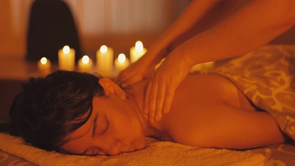 Mixed Race Ecuadorian Woman Enjoying Body Massage in Spa Salon with Candle Light