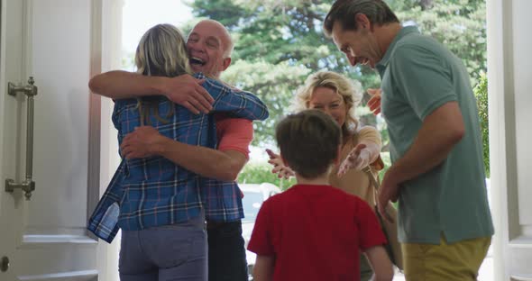 Happy caucasian couple with son opening door and greeting their grandparents
