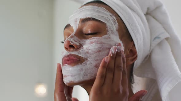 African american woman applying face mask in the bathroom at home