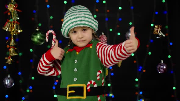 Teen Kid Girl in Christmas Elf Santa Claus Helper Costume Showing Thumbs Up on Black Background