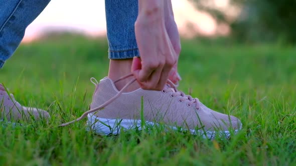 Close Up - Woman Tying Her Shoelaces on His Pink Sneakers Shoes in Outdoor.