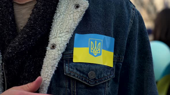 Patriot touching his chest with Ukrainian flag on jacket, close up.