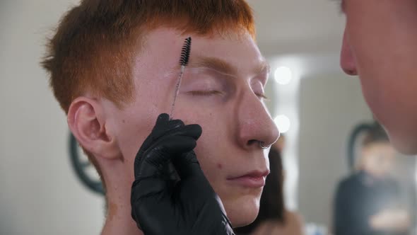 Brow Master Brushing the Hairs of Ginger Eyebrow of His Male Client