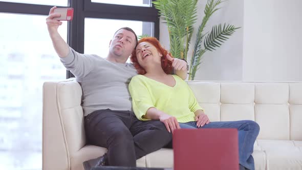 Cheerful Carefree Man and Woman Taking Selfie Sitting on Couch in Living Room