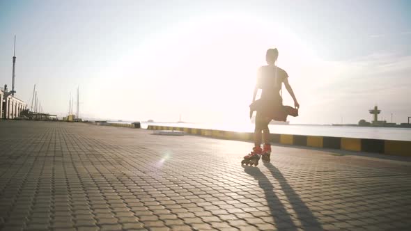 Young Stylish Funky Girl with Green Hair Riding Roller Skates on Sea Port Background During Sunset