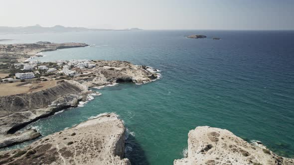 Rising shot reveals sleepy Mediterranean town overlooking turquoise blue waters. Summertime Milos Gr