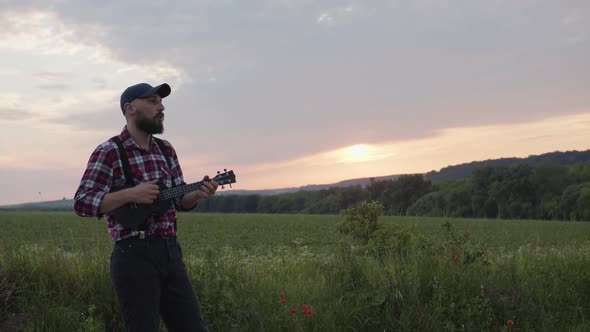 Practising Man Plays on Black Guitar on Green Field