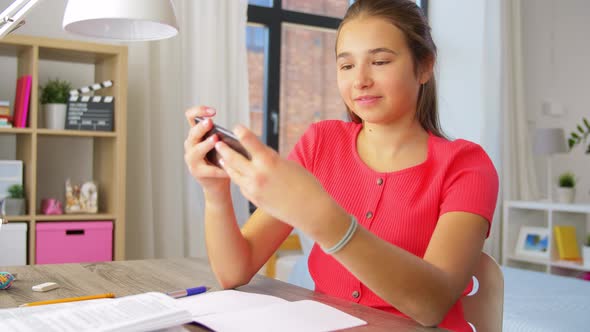 Girl with Smartphone Distracting From Homework