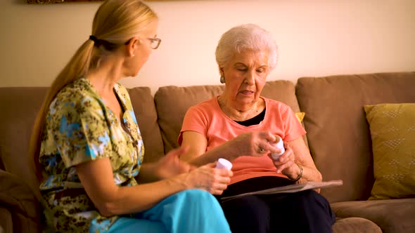 Closeup of home healthcare nurse going over medications with elderly woman while sitting in living r