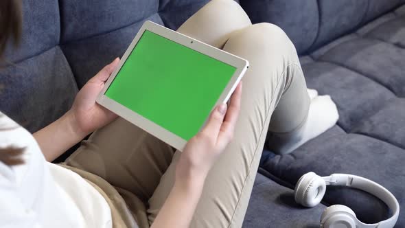 The Girl is Holding a Tablet with a Green Screen