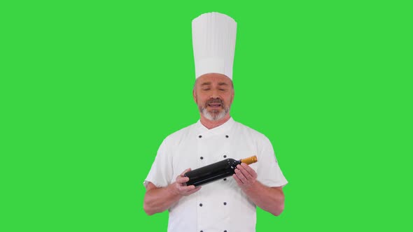 Chef in Uniform Holding a Bottle of Wine and Talking About It To You on a Green Screen Chroma Key