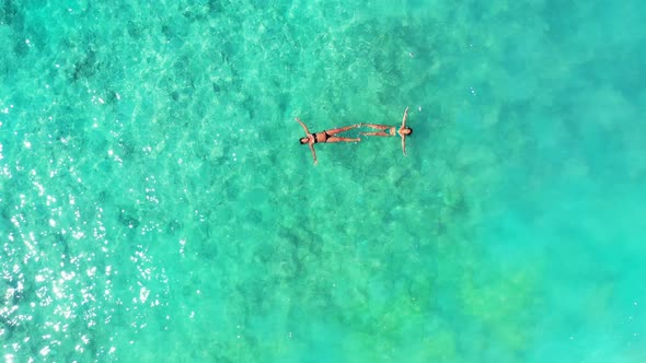 Pretty fun women on photoshoot enjoying life on the beach on clean white sand and blue 4K background