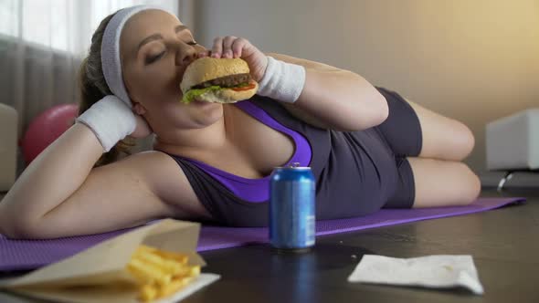 Happy Self-Confident Obese Girl Eating Greasy Burger Instead of Sports Workout