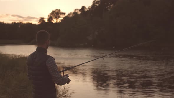 Fisherman with a spinning rod catching fish on a river.