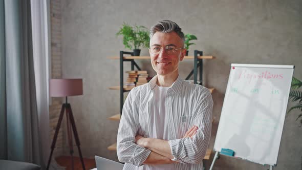 Zoom Out Portrait of Positive Confident Middle Aged Man Teacher in Eyeglasses Posing with Folded