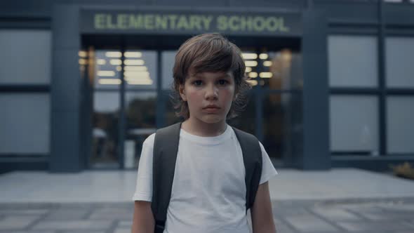 Sad Elementary Age Boy Near Modern School Entrance