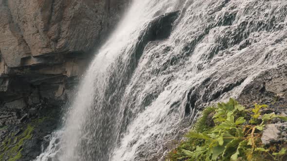 Waterfall with Foamy Water Streams Runs Down Along Rocks