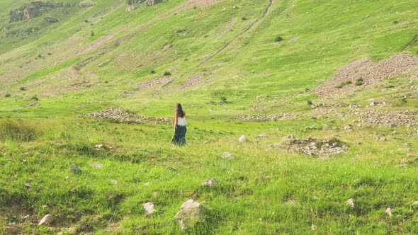 Beautiful woman in a green dress walking through a colorful green field in Barcelonnette, France.