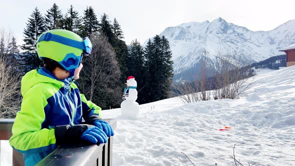 Handsome Boy with Ski Helmet and Mask on Balcony in Mountains
