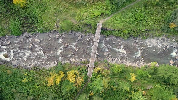 Aerial view of wood bridge crossing transparent river.