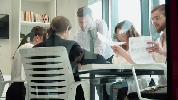 Team Leader Sitting at Table with Colleagues Discussing Working Issues at Negotiations Meeting