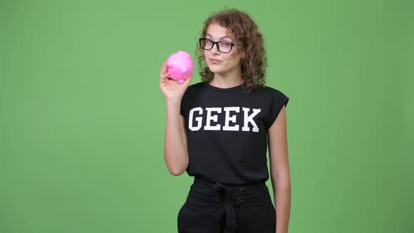 Young Beautiful Nerd Woman Thinking While Shaking Piggy Bank