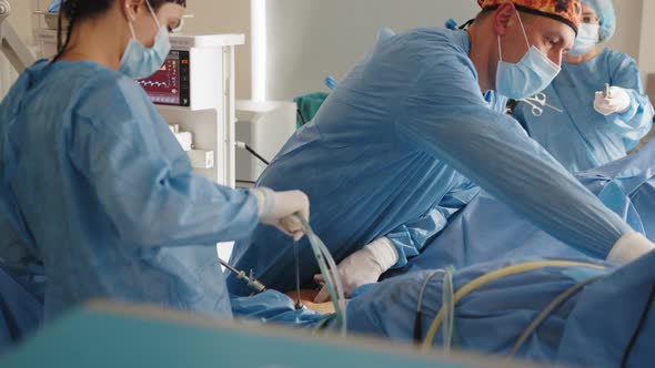 Surgery Operation Using Medical Instruments in Operating Room Looking at Screen