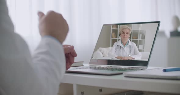 Woman Doctor Is Listening Her Colleague During Online Chat, Her Face on Screen of Notebook, Online