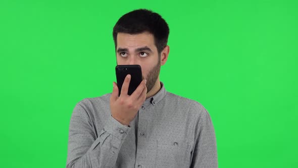 Portrait of Brunette Guy Is Asking for Information on the Network Via Phone. Green Screen