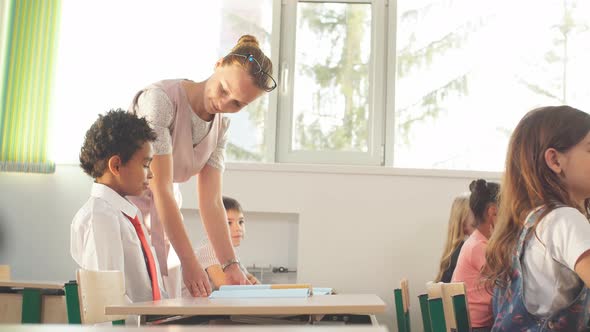 Teacher Helping Kids with Their Homework in Classroom at School