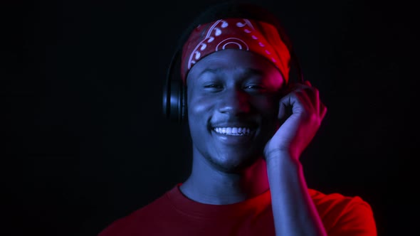 Black Guy Wearing Headphones Listening To Music In Dark Studio