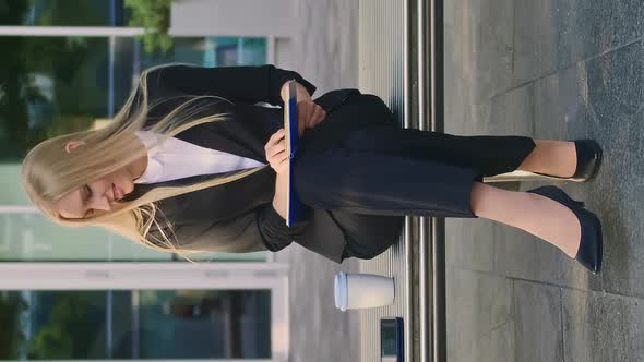 Girl with Notepad Speaking on Phone Outdoors. Modern Business Woman in Suit Sitting on Bench with