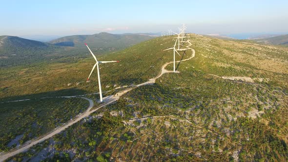 Flying above elegant ecological wind turbines on green hills